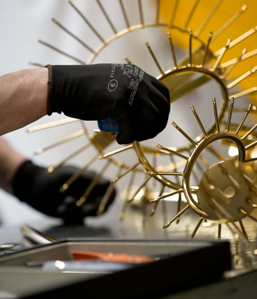 Lavorazione a mano di una struttura metallica dorata per lampadario in officina